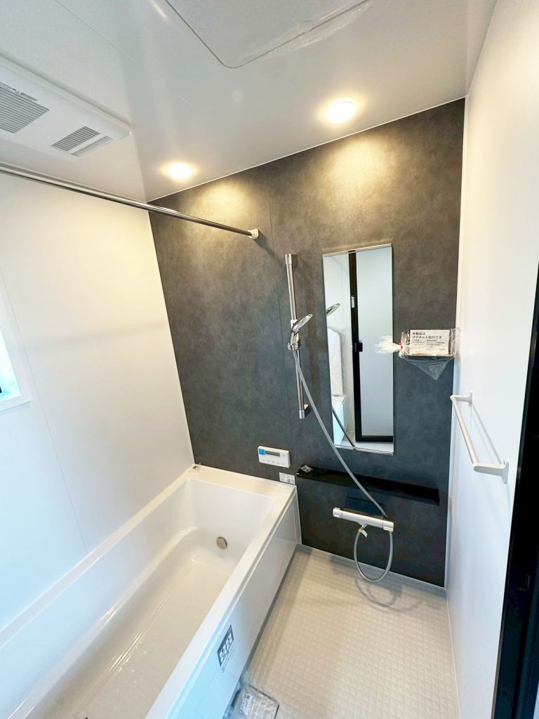 画像:ダークグレーのアクセントパネルが空間を引き締め、まるでホテルのような上質なバスルーム