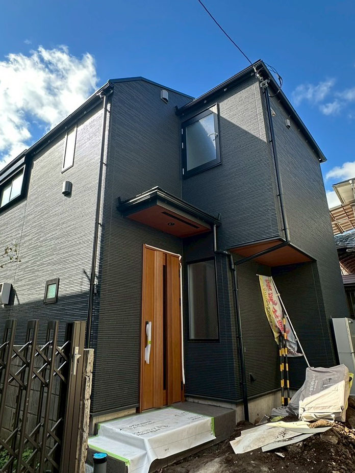 画像:ダークトーンの外観+ウッド調の玄関ドアが高級感を演出